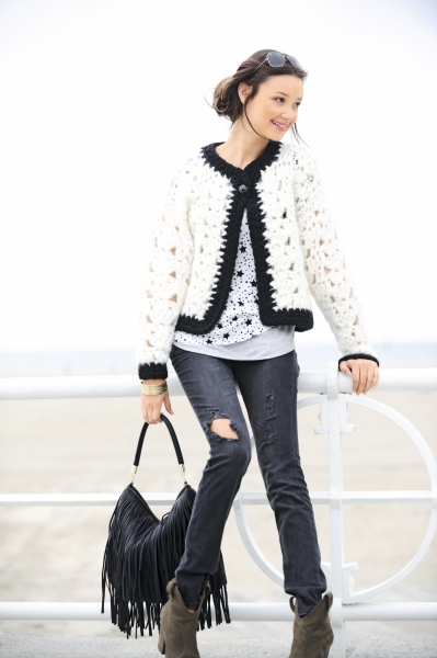 Weiß-schwarze DIY-Häkeljacke, gemustertes Shirt, zerrissene Jeans, Fransenhandtasche, modisch handgemacht.