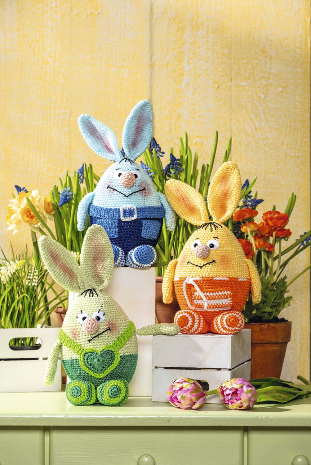 Bunte, handgemachte Häkelhasen in Blau, Gelb und Grün mit kontrastreichen Mustern. DIY Handarbeit, fröhlich gestaltet.