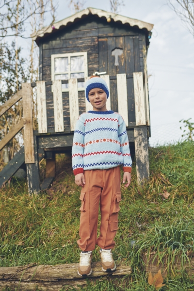 Selbstgemachter Pullover mit buntem Zickzack-Muster, kombiniert mit schlichten Cargohosen in warmem Rotton.