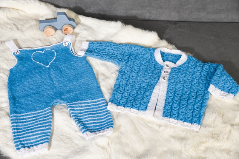 Modische blaue Strickjacke und Latzhose mit Herz-Muster, handgemacht, mit weißen Akzenten und Streifen.