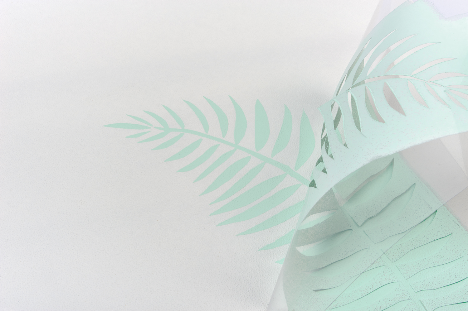 Mintgrünes, geschnittenes Blattmuster auf Papier. Kreativ, handgemacht, DIY-Stil, zart.