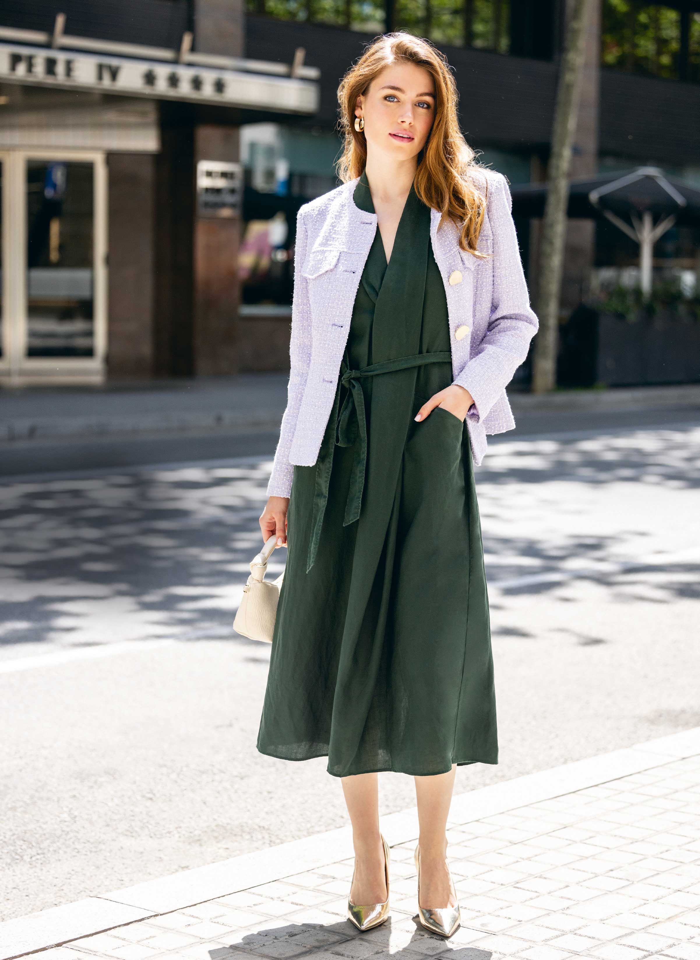 Lila Jacke mit großen Knöpfen, fließendes grünes Kleid, schimmernde Schuhe. Stilvoll, elegant, zeitlos.