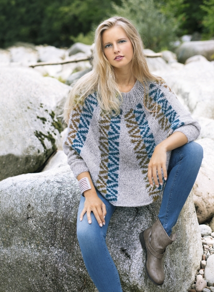 Grauer, handgemachter Pullover mit blau-grünem Zickzackmuster. Schlanke Jeans, beige Stiefel. Stilvoll und DIY.