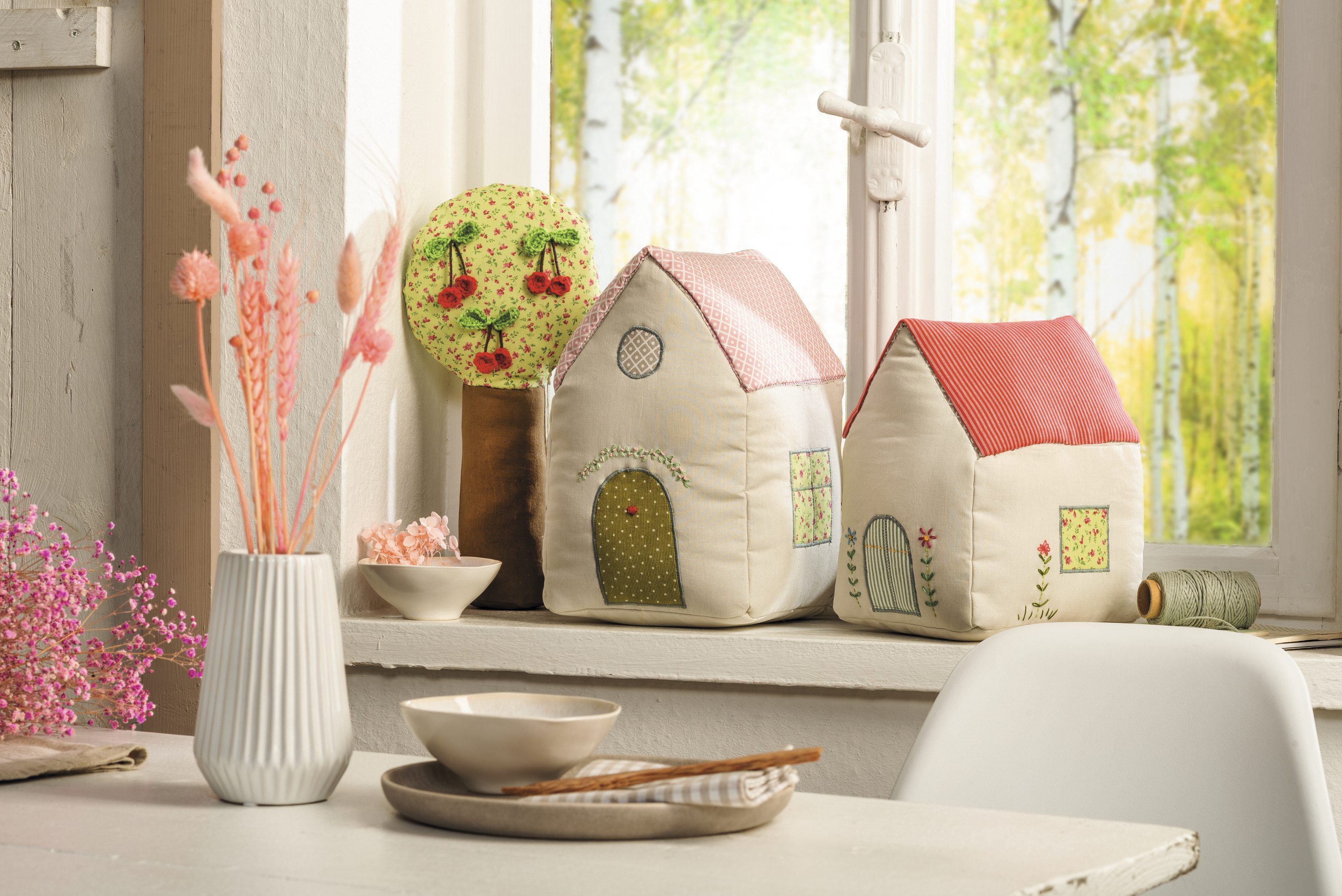 Zwei handgemachte Stoffhäuser mit floralen Mustern und pastellfarbenen Dächern, modisch und kreativ gestaltet.