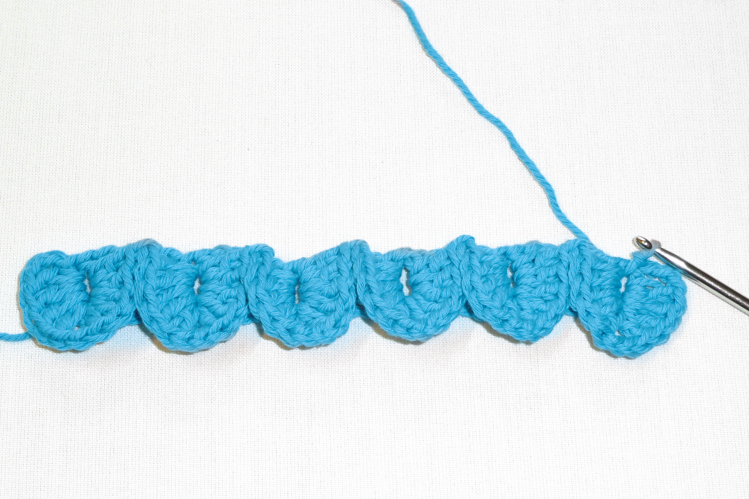 Selbstgemachtes Häkelmuster in kräftigem Blau, wellenförmig, einzigartiger DIY-Stil, handgefertigt.