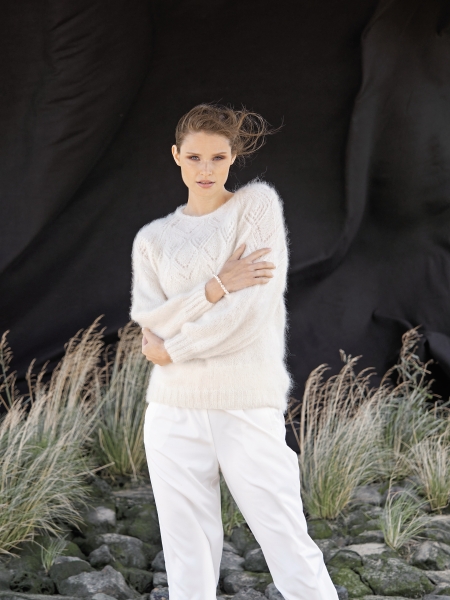 Weißer, flauschiger Strickpullover mit Zopfmuster, kombiniert mit locker geschnittener, weißer Hose. Minimalistisch, modisch.