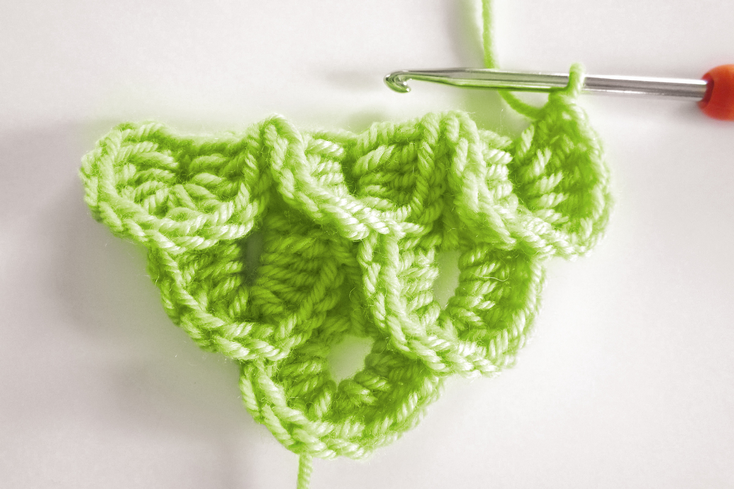 Selbstgemachtes, leuchtend grünes Häkelstück mit markantem Wellenmuster. Kreative DIY-Handarbeit.