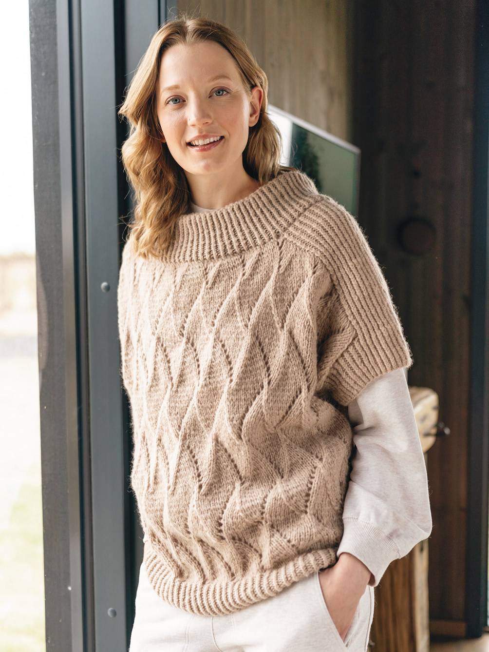 Handgemachter, beigefarbener Strickpullover mit Zopfmuster. Lockerer Schnitt, warm und modisch.