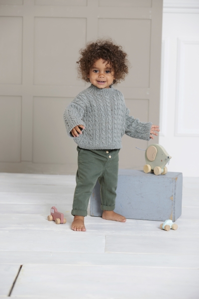 Gestrickter grauer Pullover mit Zopfmuster, kombiniert mit grüner Hose. Selbstgemacht-Charme. Bequem und stilvoll.