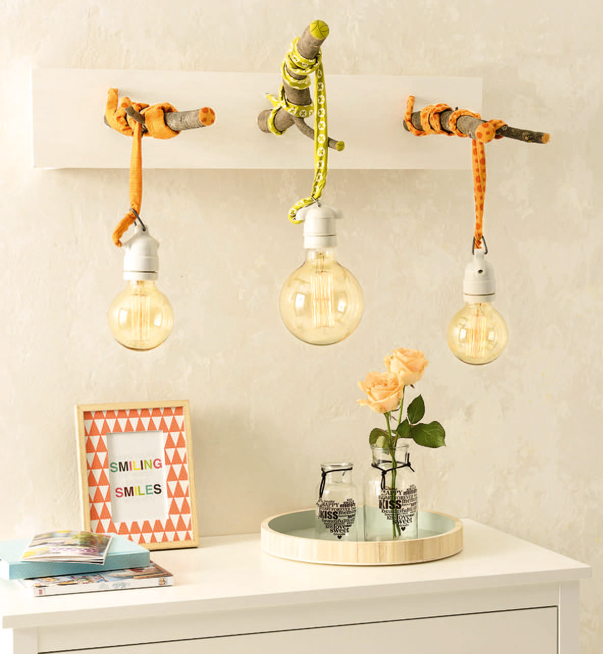 Handgemachte Lampen mit bunten Seilen, rustikalen Ästen und großen Glühbirnen; Retro und DIY Charme.