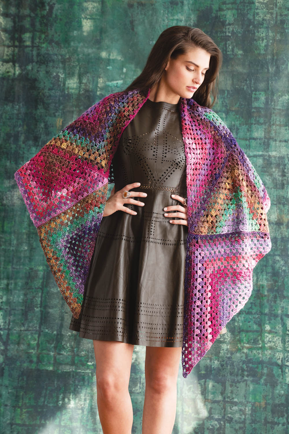 Modische gehäkelte Stola in bunten Farben über schwarzem, perforiertem Kleid. DIY, handgemacht, lebhaft.