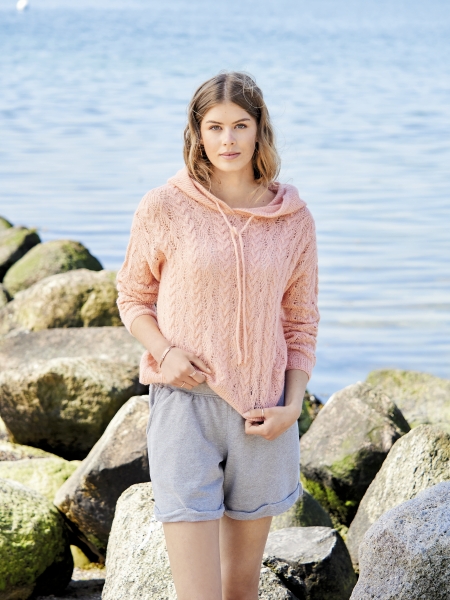 Modischer, handgemachter Hoodie in Pfirsichton mit Zopfmuster, kombiniert mit grauen Shorts.