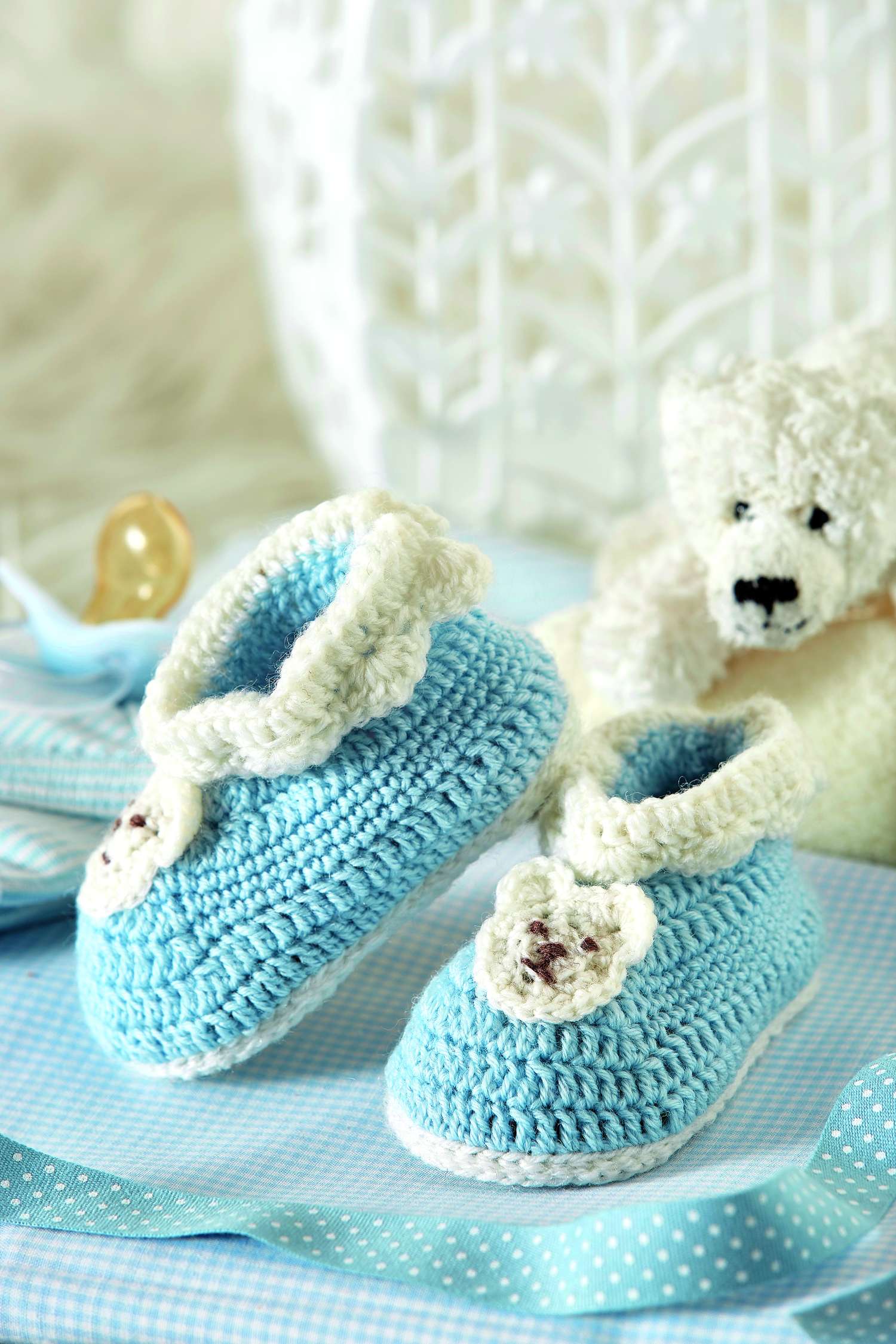 Modische, handgemachte Babyschuhe in Blau mit weißer Spitze und Bärenmotiv, gestrickt. DIY-Charme.