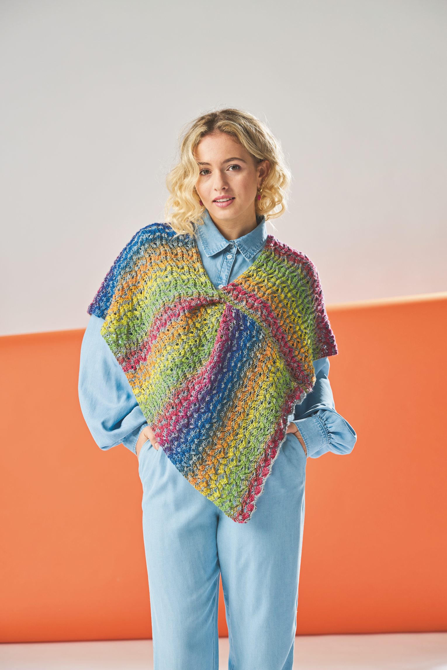 Modischer, selbstgemachter Poncho in Regenbogenfarben, lockeres Muster. Kombiniert mit hellblauem Hemd.