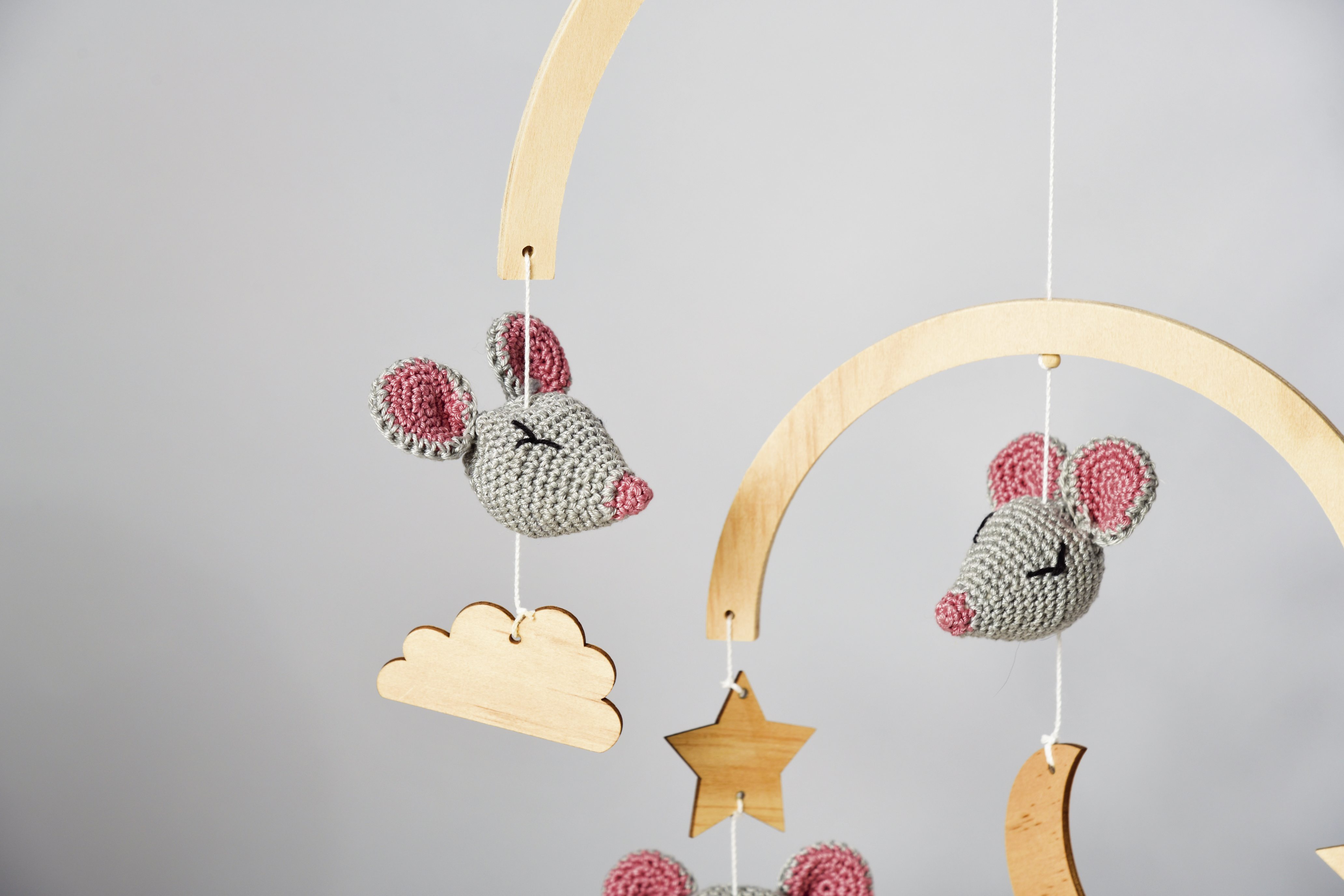 Graue und rosa gehäkelte Mäuse als DIY-Mobile. Minimalistische Form mit Holzsternen und Wolken.