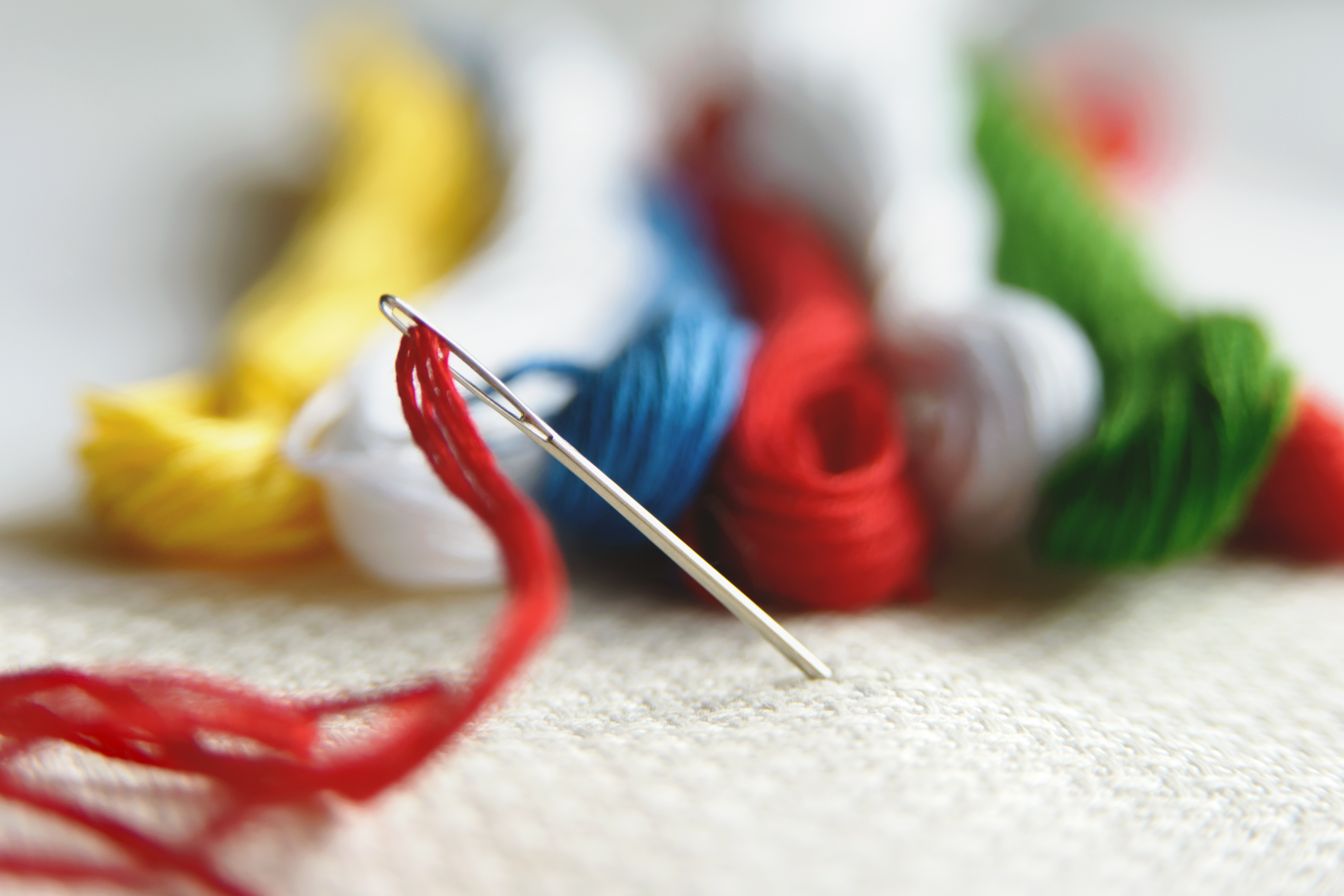 Bunte Stickgarne in Rot, Blau, Grün und Gelb. Handarbeit, modisch und DIY-inspiriert.