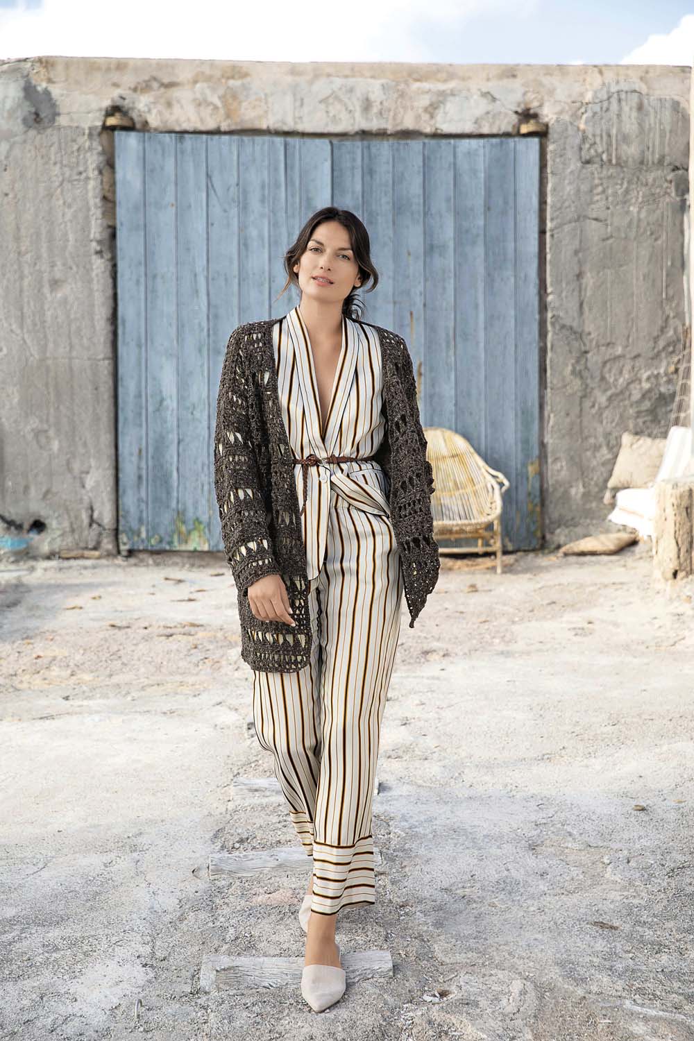 Gestreifter, fließender Jumpsuit, kombiniert mit handgemachtem, gehäkeltem Cardigan in Erdtönen. Modisch und elegant.