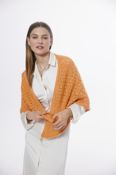 Orange, handgemachtes, gehäkeltes Tuch über cremefarbenem Kleid. Elegante, modische Kombination.