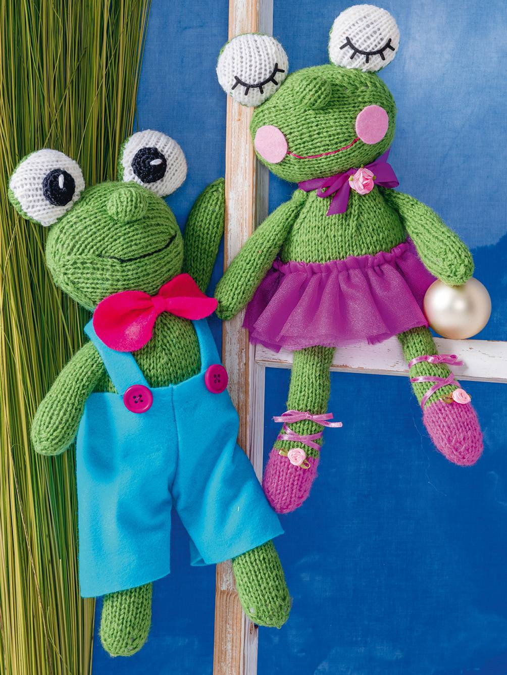 Handgemachte Frösche in Blau und Lila, mit Schleife und Stoffrock. Niedliche DIY-Strickmode.