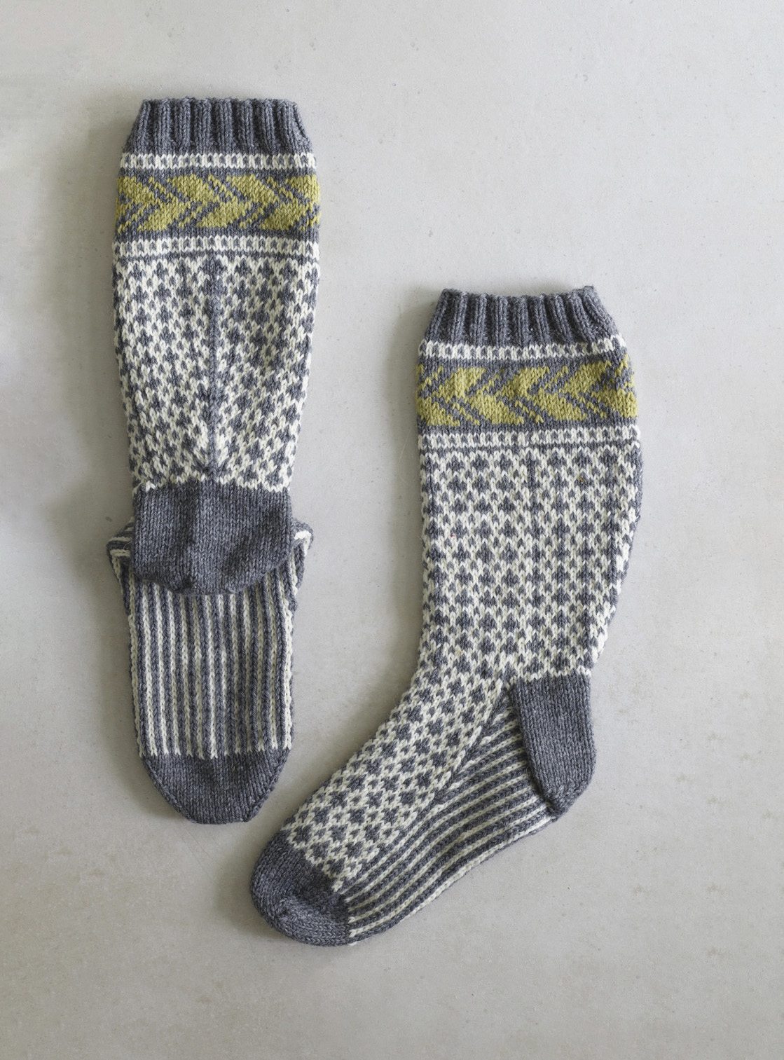 Graue handgestrickte Socken mit geometrischem Muster und gelben Akzenten. Modisch und aufwendig gearbeitet.