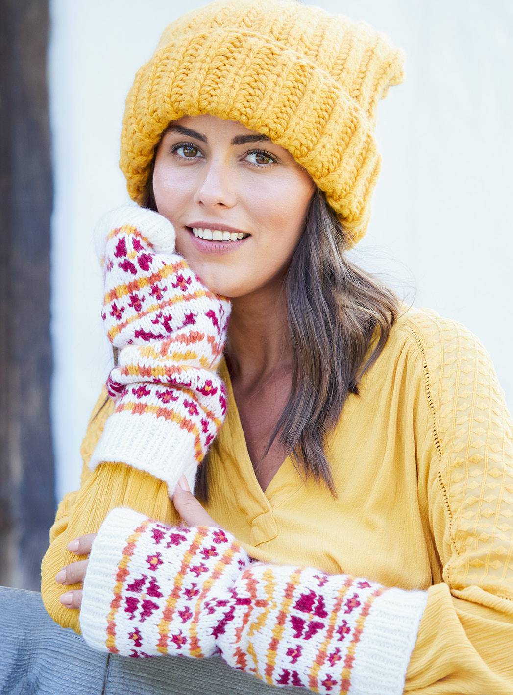 Modisch gestrickte Mütze in Gelb, farbenfrohe, gemusterte Armstulpen, handgemacht und stilvoll.