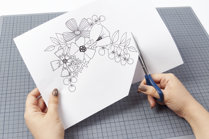 Papier mit floralen, skizzierten Motiven wird kunstvoll ausgeschnitten. Kreative DIY-Handarbeit.