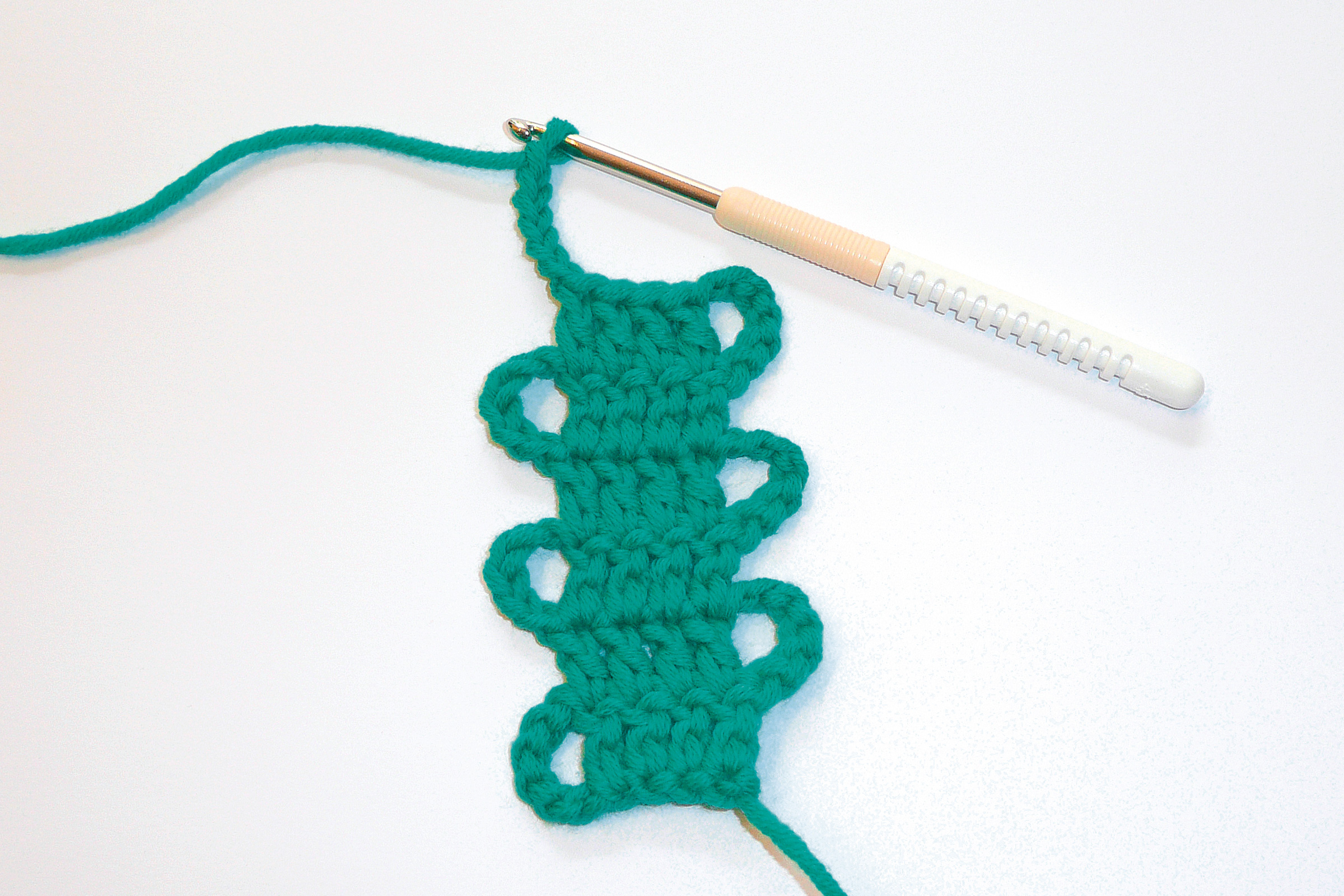 Türkises Häkelstück, spiralförmig, handgefertigt mit Häkelnadel. Modisch, DIY, Handarbeit.