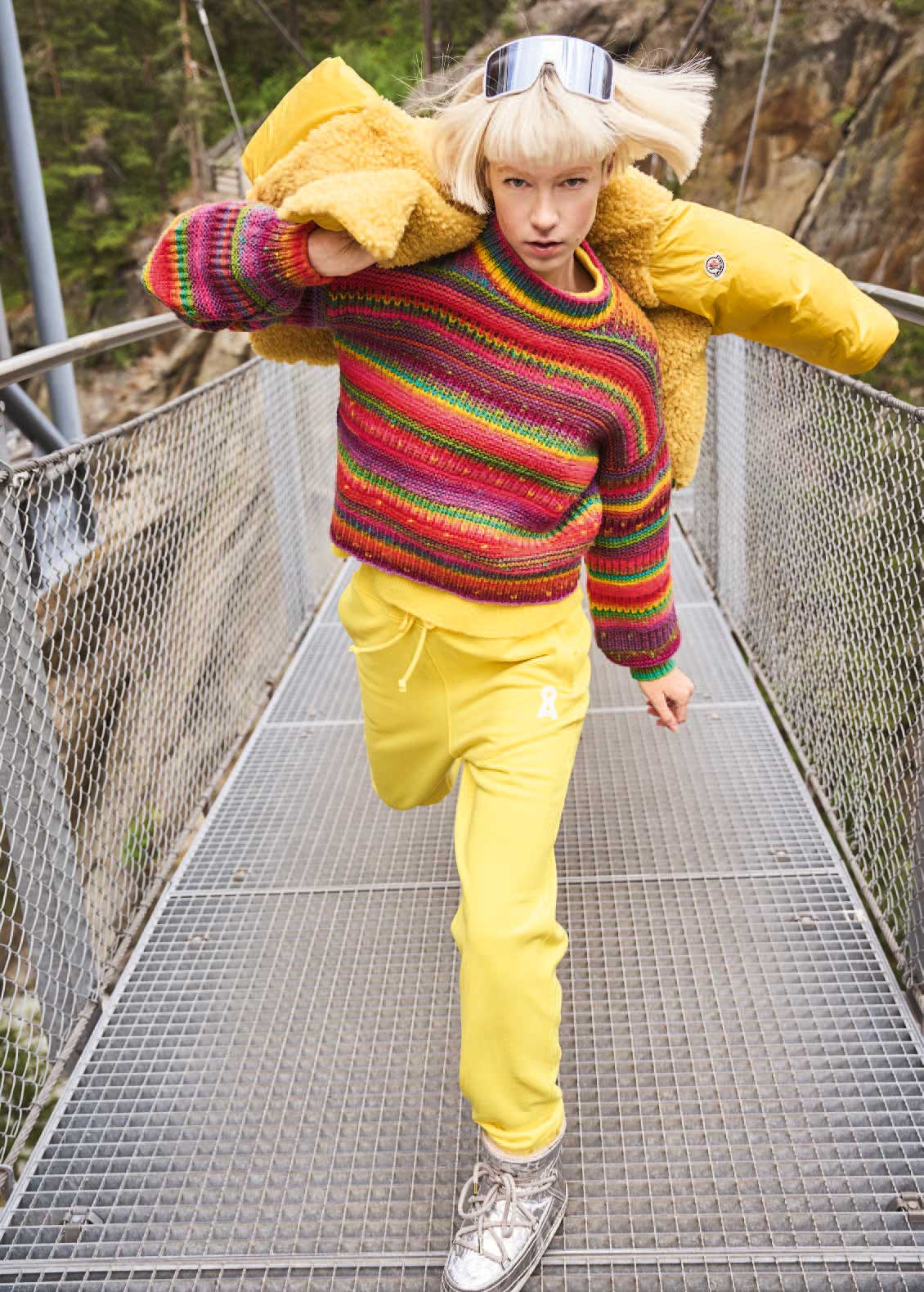 Bunter Strickpullover, gelbe Jogginghose, silberne Schuhe, Daunenjacke - modisch & auffällig.