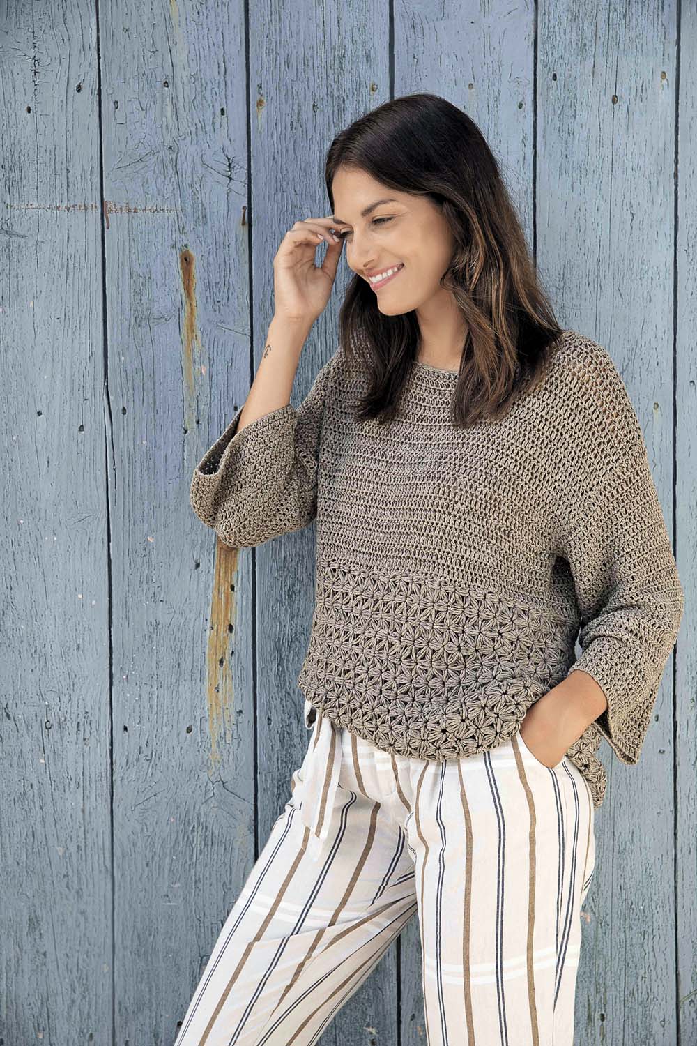 Modischer, handgemachter Pullover in Erdtönen, kombiniert mit gestreifter Hose. Perfekte Mischung aus DIY und Stil.