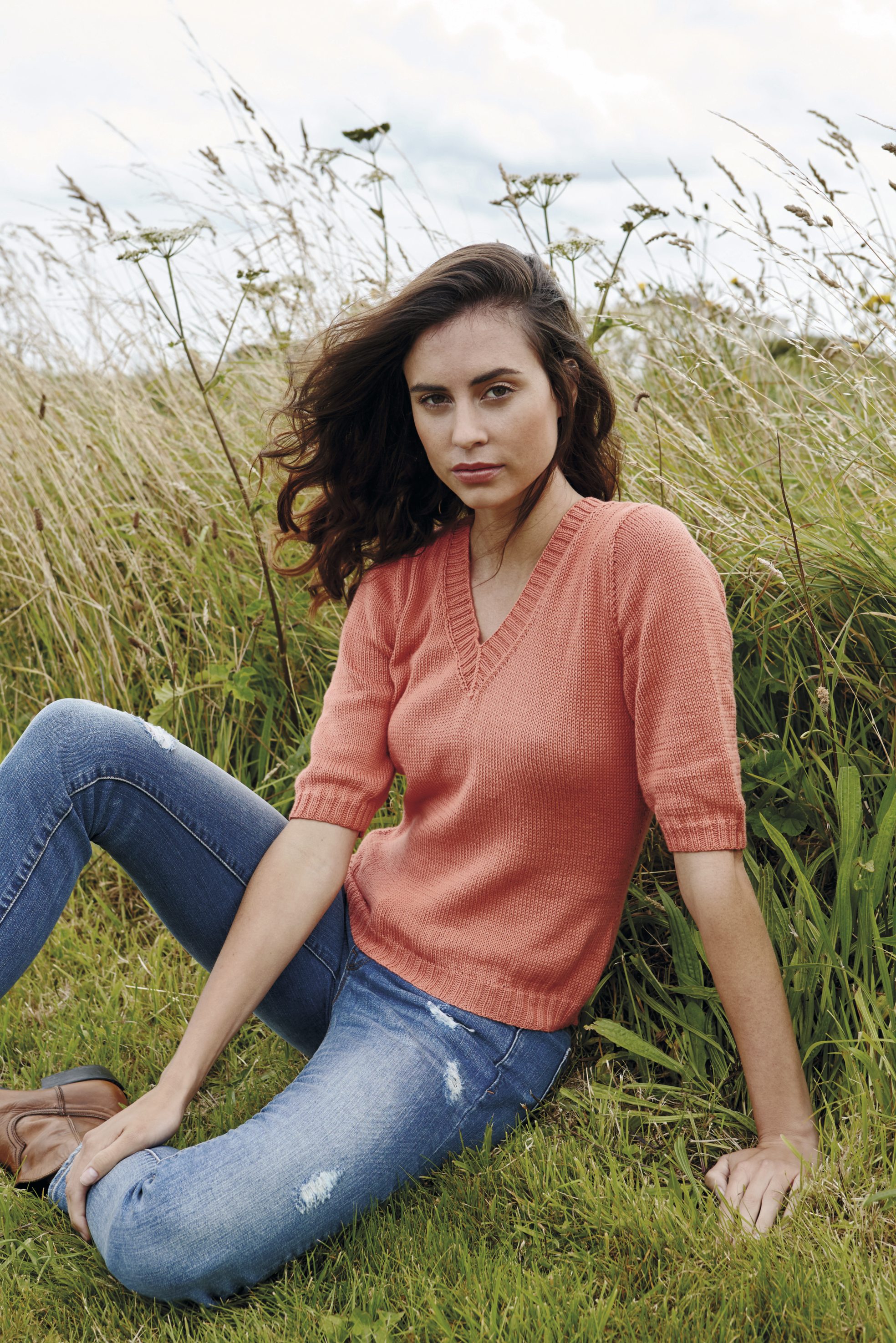 Korallener Strickpullover, halbärmlig mit V-Ausschnitt gepaart mit zerrissenen Jeans. Trendig und handgemacht.