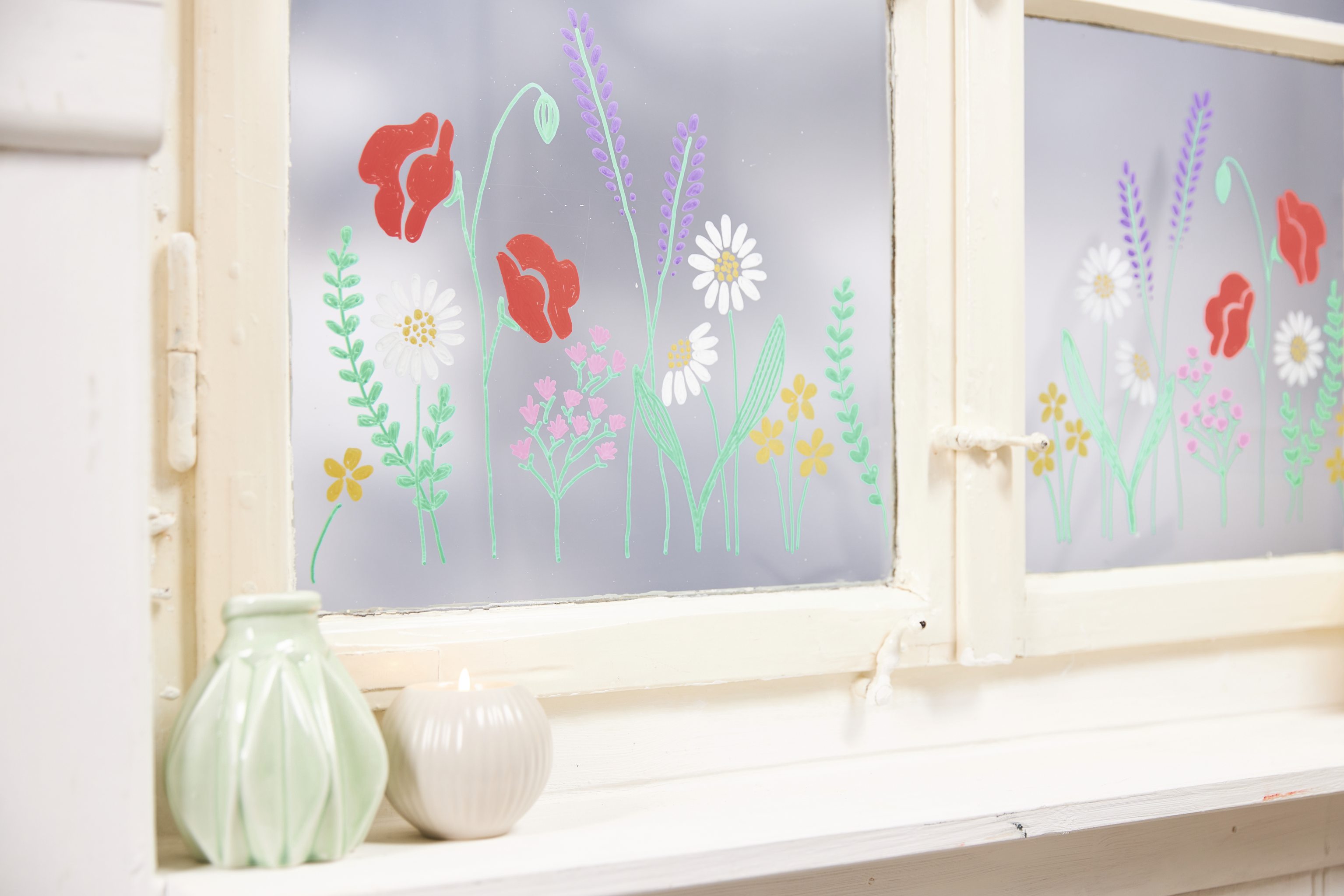 Fensterdeko mit farbigen Blumenmustern. DIY-Stil, lebendige Farben, kreative und natürliche Gestaltung.