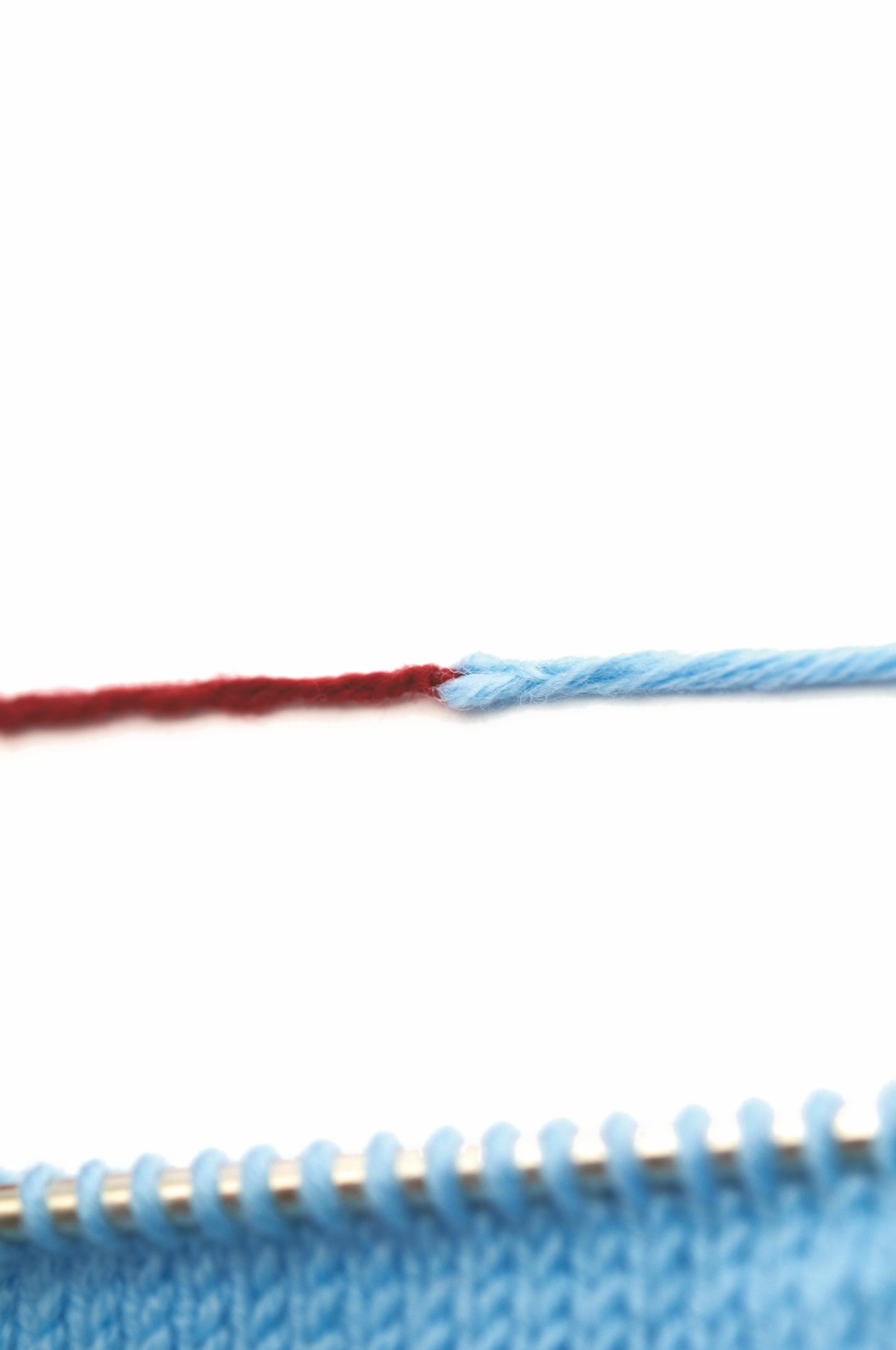 Handarbeit mit blauem Garn und rotem Akzent, DIY-Charme, gleichmäßige Maschen auf Stricknadel.