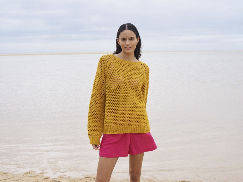 Gelber, gehäkelter Pullover, luftige Struktur; kombiniert mit pinken Shorts. Modisch, handgemacht, sommerlich.