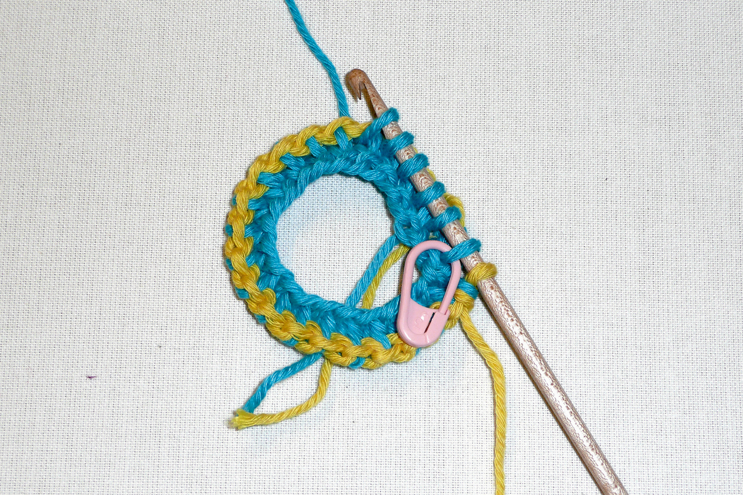 Buntes Strickprojekt, türkis-gelbe Maschen, handgemacht, DIY, Häkelnadel, Startmarker.