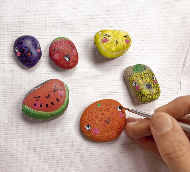 Bunte, handbemalte Steine mit Fruchtmotiven, DIY-Stil. Lebendige Farben: Gelb, Rot, Lila. Kreativ und einzigartig.