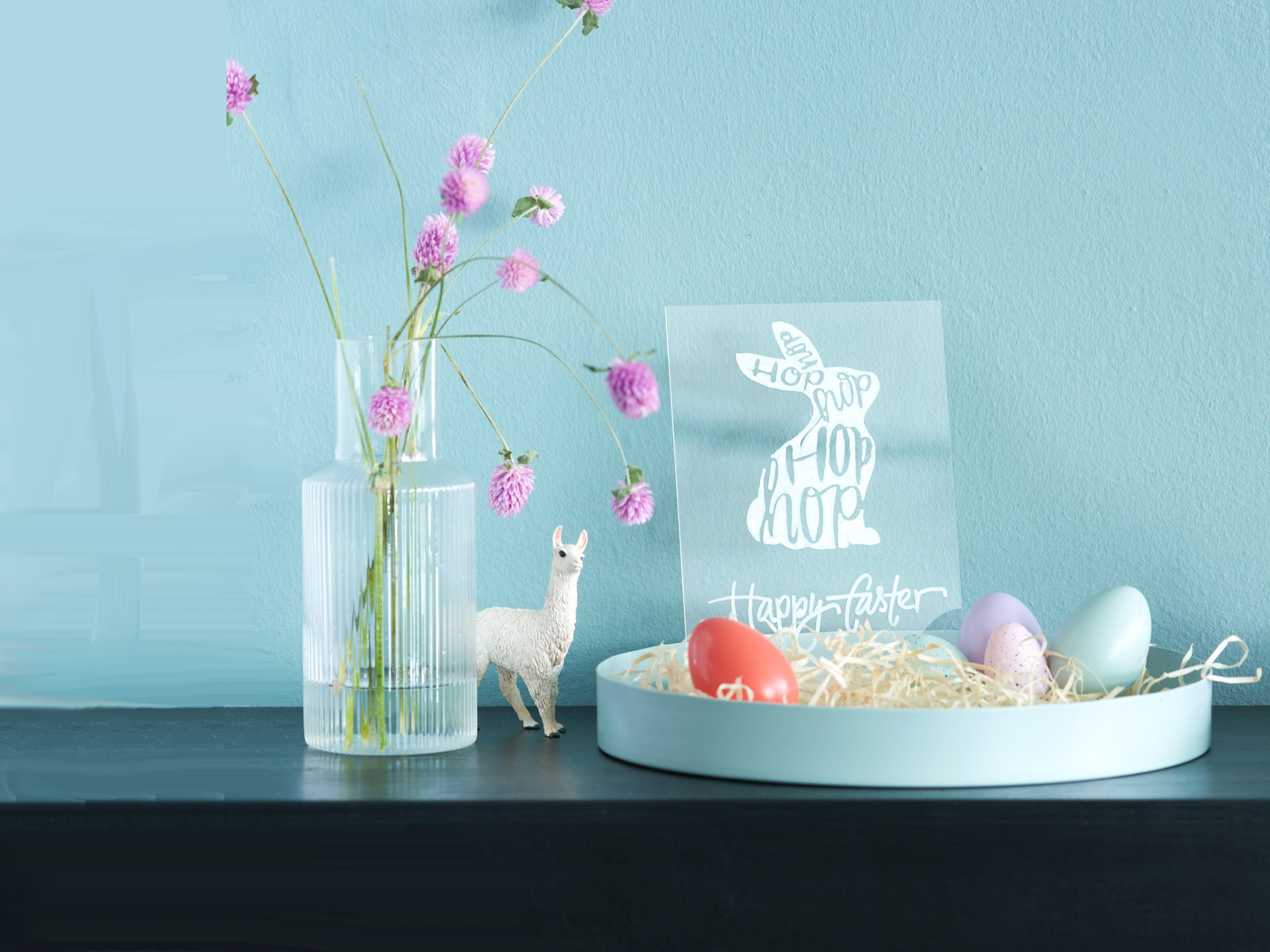 Pastellfarbene Ostereier im DIY-Stil, Glasvase mit Blumen, süße Lama-Figur, minimalistische Osterkarte im modernem Design.
