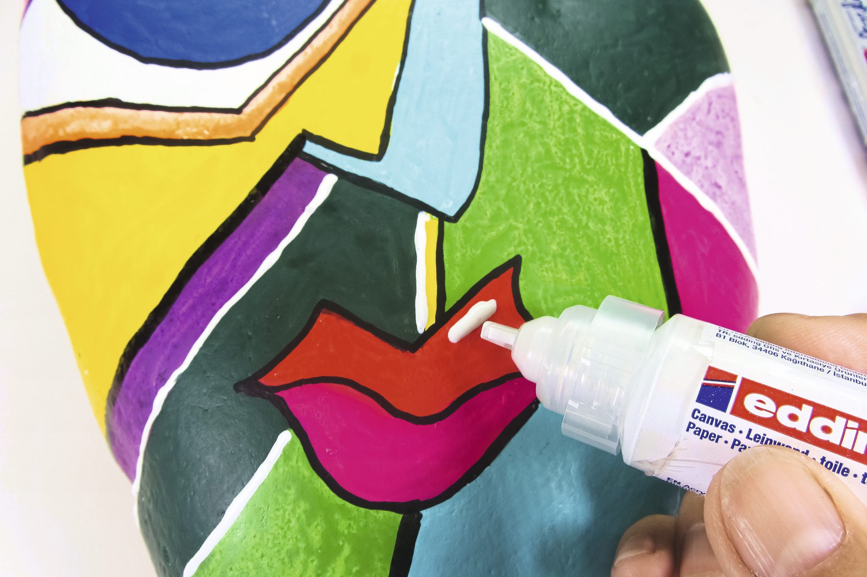 Bunte, abstrakte Muster auf bemalter Maske; kräftige Farben; DIY-Stil; handgefertigt und modern.