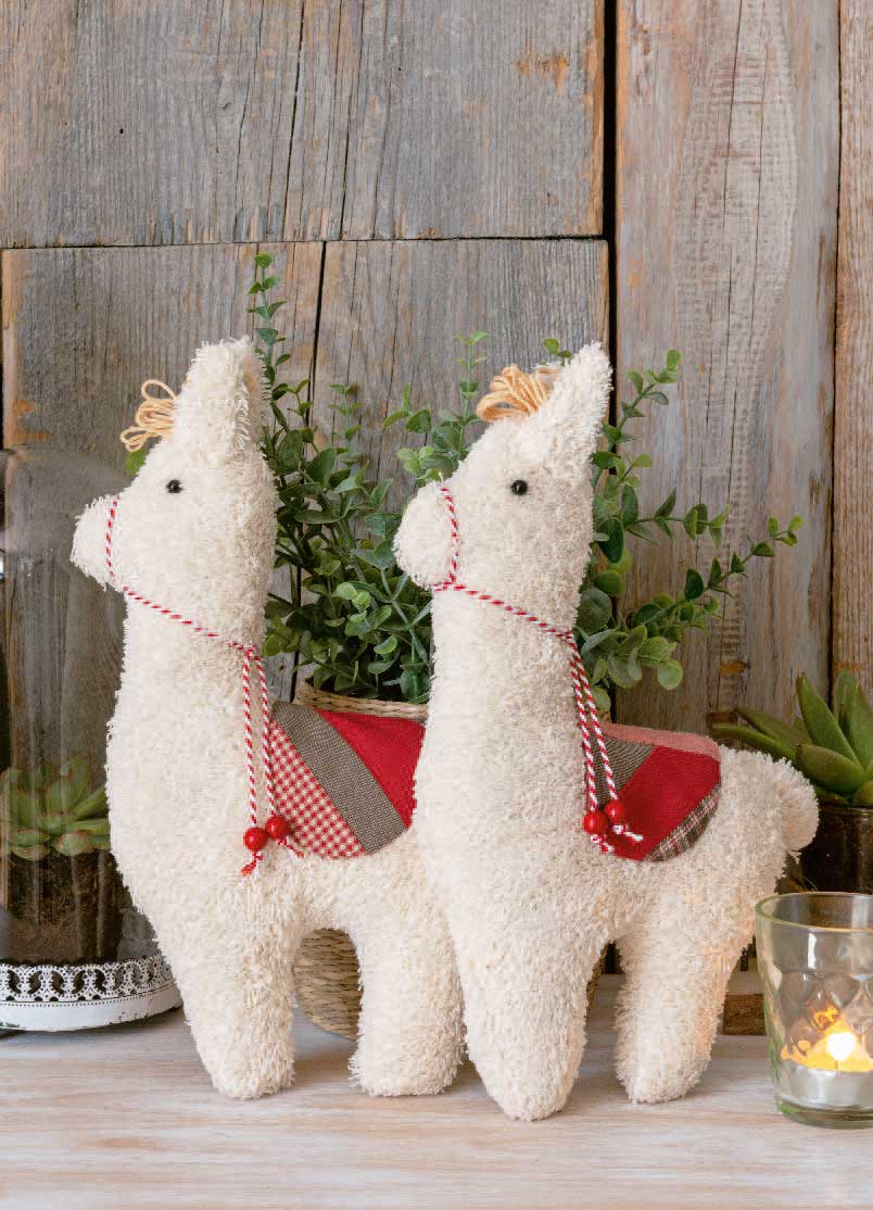 Handgemachte Lamas aus flauschigem Material, mit rotem Karo-Sattel und Detailverzierungen. DIY, gemütlich.