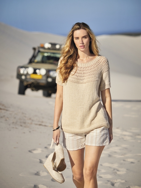 Beigefarbener Strickpullover, luftiges Muster, kombiniert mit hellen Shorts; modisch, handgemacht.