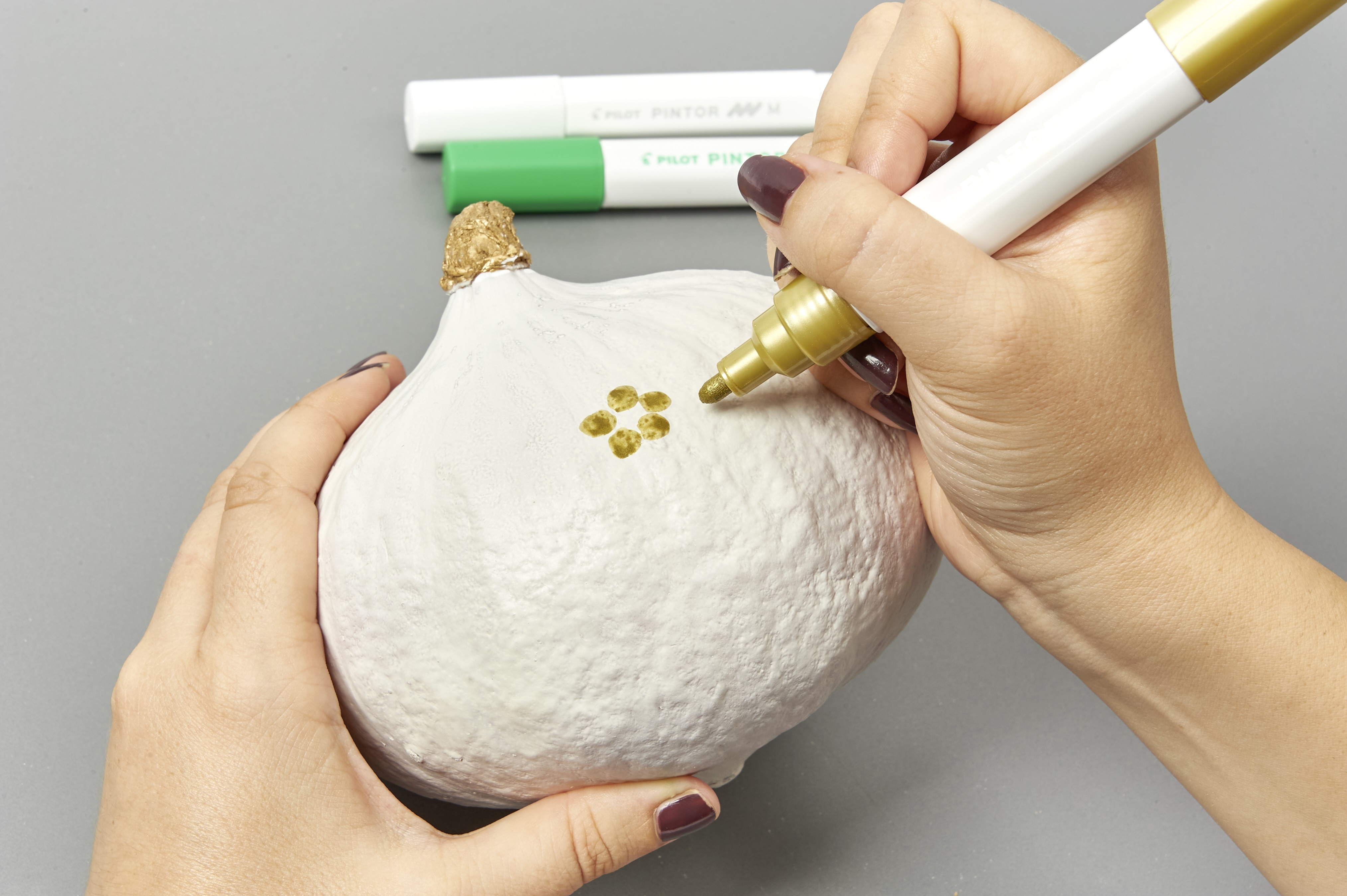 DIY: Weißer Kürbis mit goldener, handgemalter Blume verziert. Modisch, einzigartig gestaltet.