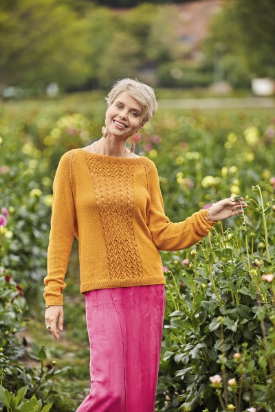 Senfgelber Strickpulli mit Zopfmuster, kombiniert mit leuchtend rosa Rock. Modisch, handgemacht, lebendig.