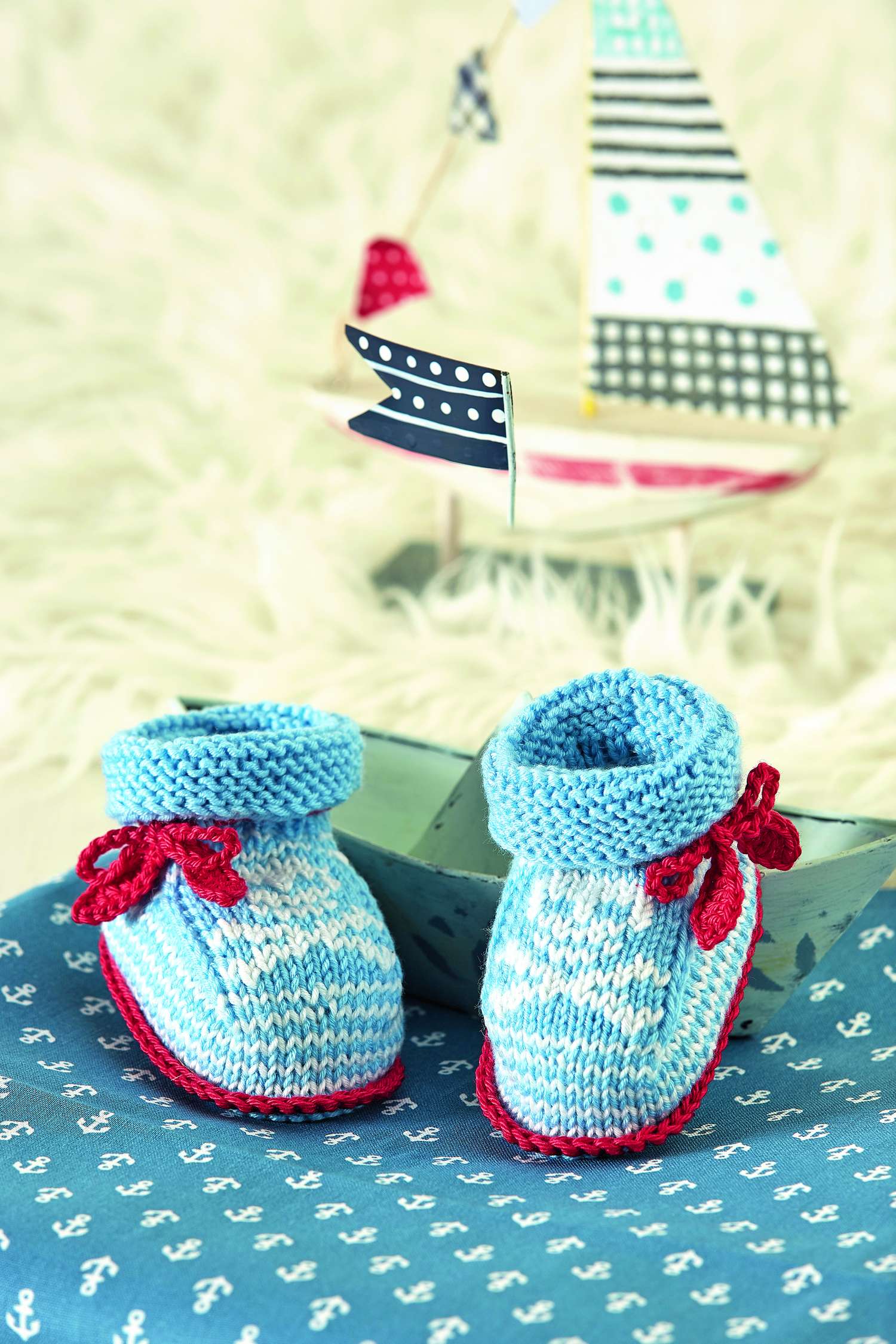 Modische, handgestrickte, blaue Booties mit roten Schleifen; DIY-Look, weiches Muster, perfekte Handarbeit.