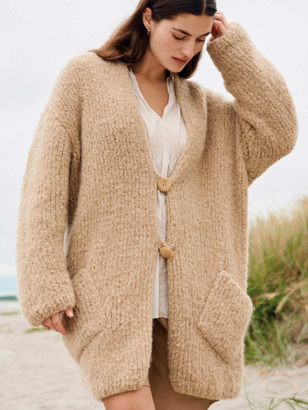 Oversized Strickjacke, beige, grobes Muster, große Knöpfe, handgemacht, modisch, warme Herbstkleidung.