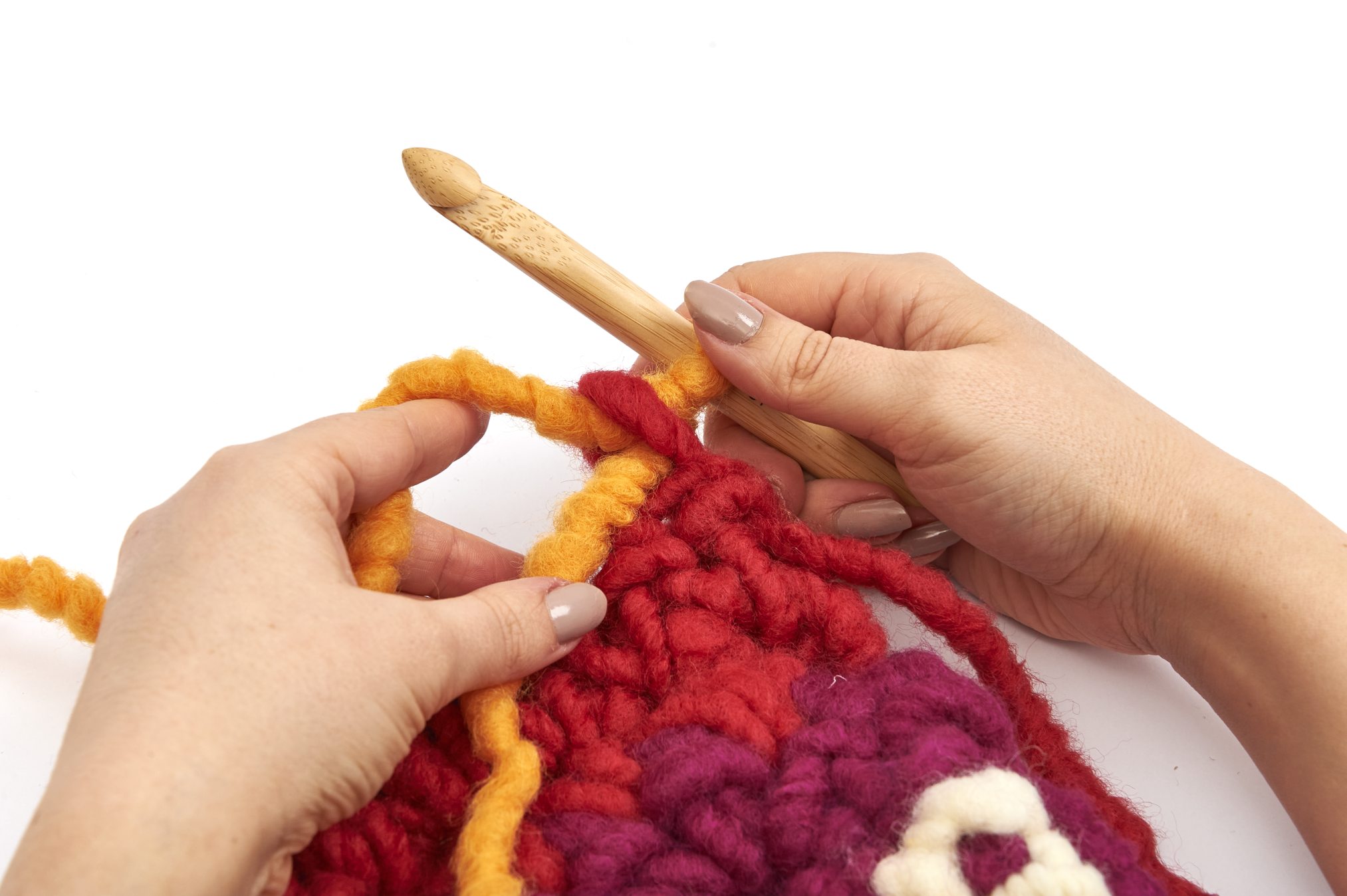 Bunte, handgemachte Häkelmaschen. Rote, lila und gelbe Wolle mit DIY-Charme. Handarbeits-Muster.