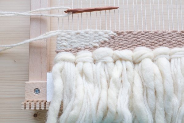 Grobes handgemachtes Webstück in Creme- und Beigetönen. Flauschige Textur, DIY-Charme.