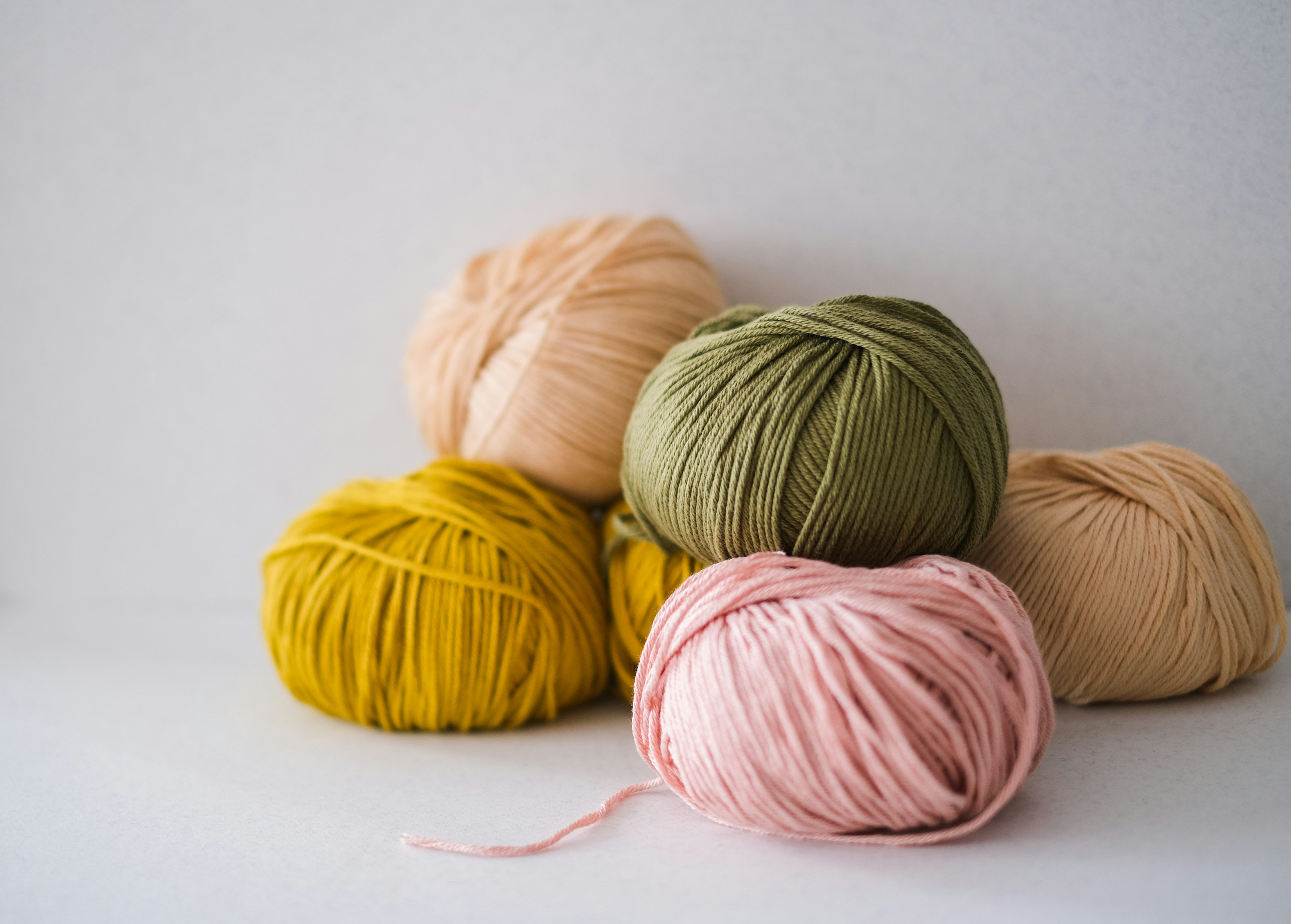 Weiches Garn in sanftem Grün, Rosa, Gelb und Beige. Perfekt für handgemachte DIY-Projekte und modische Handarbeiten.