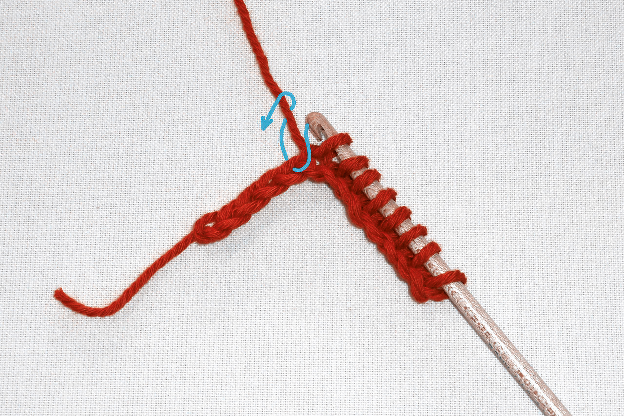 Rotes Garn in DIY-Häkelarbeit, dichte Maschen, elegante Struktur, handgemacht mit pinkfarbener Nadel.