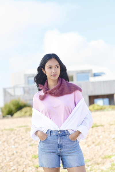 Modischer Look: Rosa Shirt, locker geknoteter pinker Schal, offene weiße Bluse, blaue Denim-Shorts.