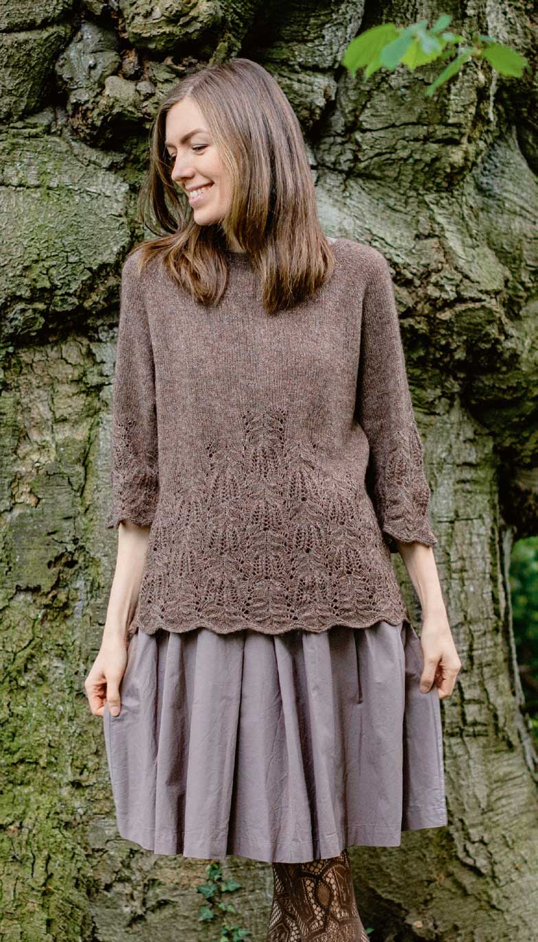 Brauner, handgemachter Pullover mit filigranem Muster und weicher Textur, kombiniert mit grauem, weitem Rock.