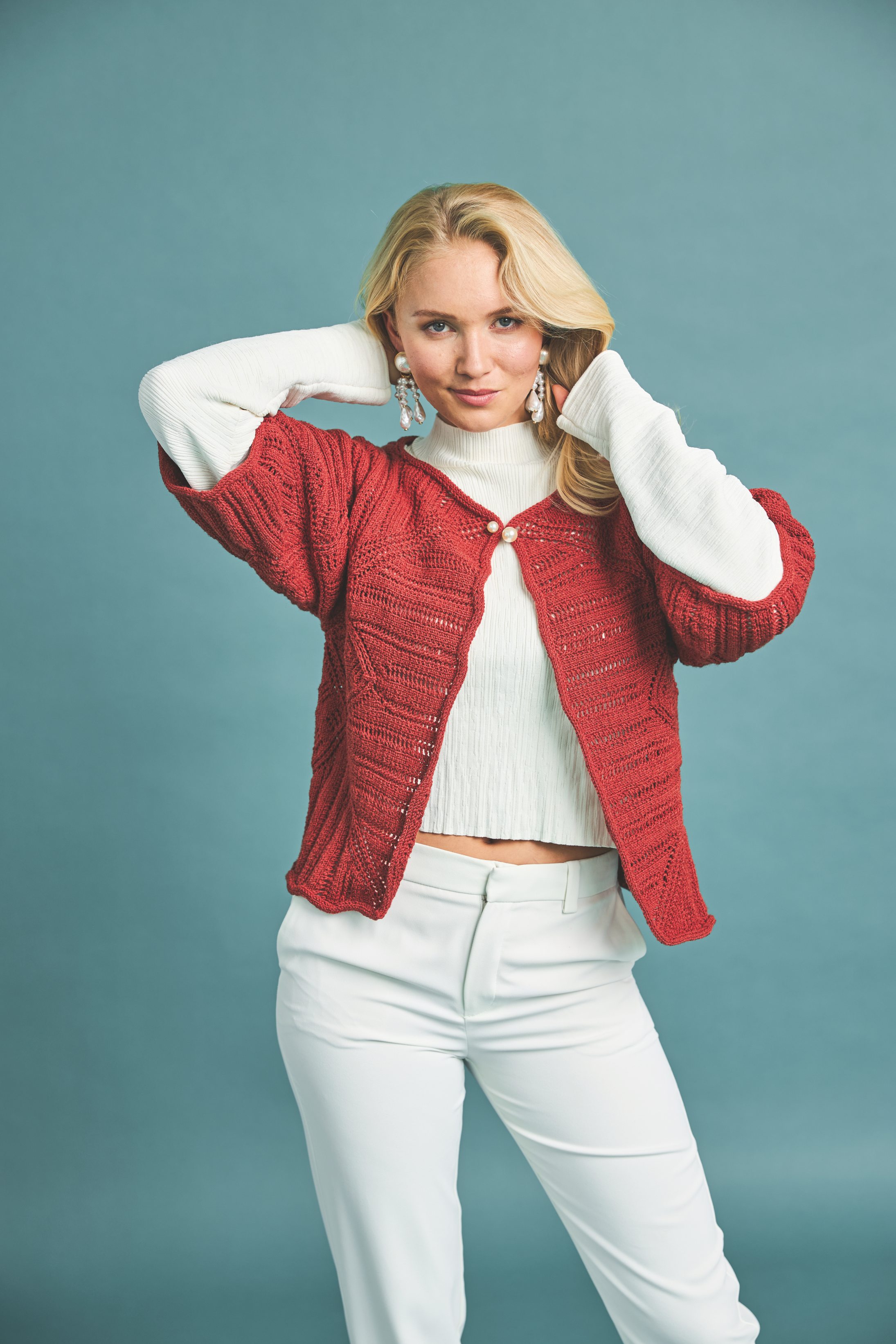 Rote, handgemachte Strickjacke über weißem Top. Weite Ärmel, modisch, selbstgemacht, elegant.